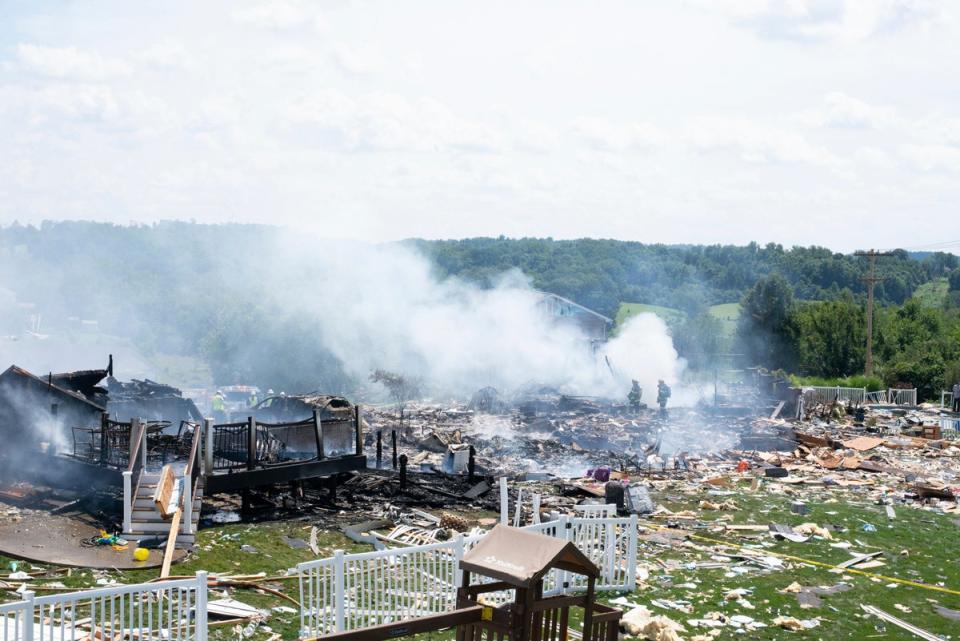 Two firefighters stand on the debris around the smoldering wreckage of the the three houses (Pittsburgh Post-Gazette)