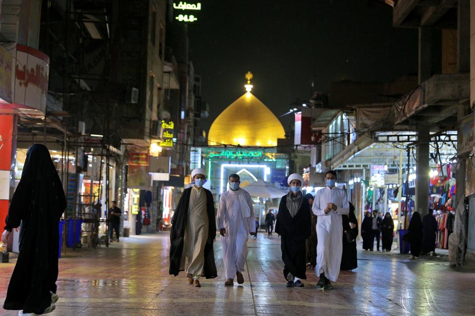 In this Monday, Feb. 24, 2020 photo, Shiite pilgrims wear masks outside the shrine of Imam Ali in Najaf, Iraq. The Health Ministry said four new cases of coronavirus were diagnosed in the northern province of Kirkuk. It said the afflicted were members of an Iraqi family who had returned from a recent trip to Iran. Iraq announced the discovery of the first coronavirus case in the country on Monday in Najaf. Iraq had earlier closed its border with Iran to Iranian nationals but apparently Iraqis can still cross the boundary. (AP Photo/Anmar Khalil)