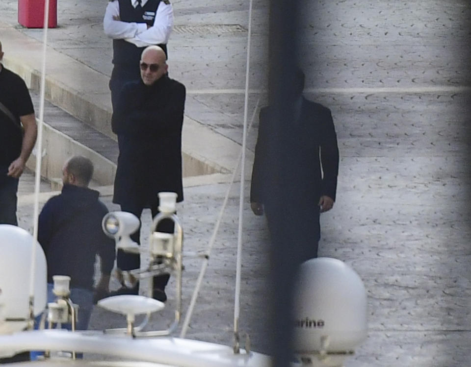 Maltese businessman Yorgen Fenech, wearing dark sunglasses, is accompanied by police during a search of his yacht at the dock of Portomaso, Malta, Friday, Nov. 22, 2019. Fenech was arrested Wednesday, then released on police bail late Thursday as investigators try to find a mastermind of the 2017 murder of investigative reporter Daphne Caruana Galizia on the small island nation. (AP Photo/stringer)