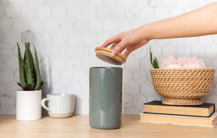 A hand placing a wooden lid on the jar in dolphin