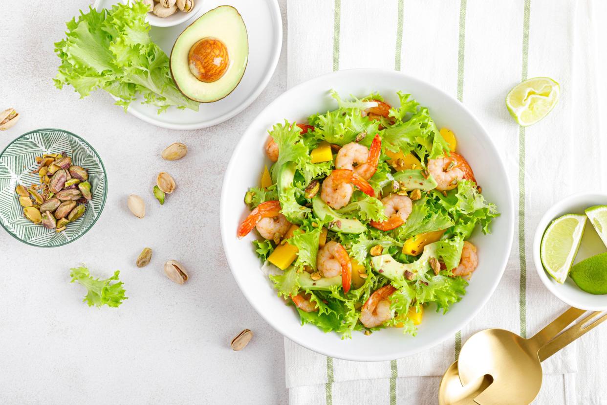 Grilled shrimp salad with avocado, mango, lettuce and pistachios, dressed with lime. Healthy food. Ketogenic diet. Top view.