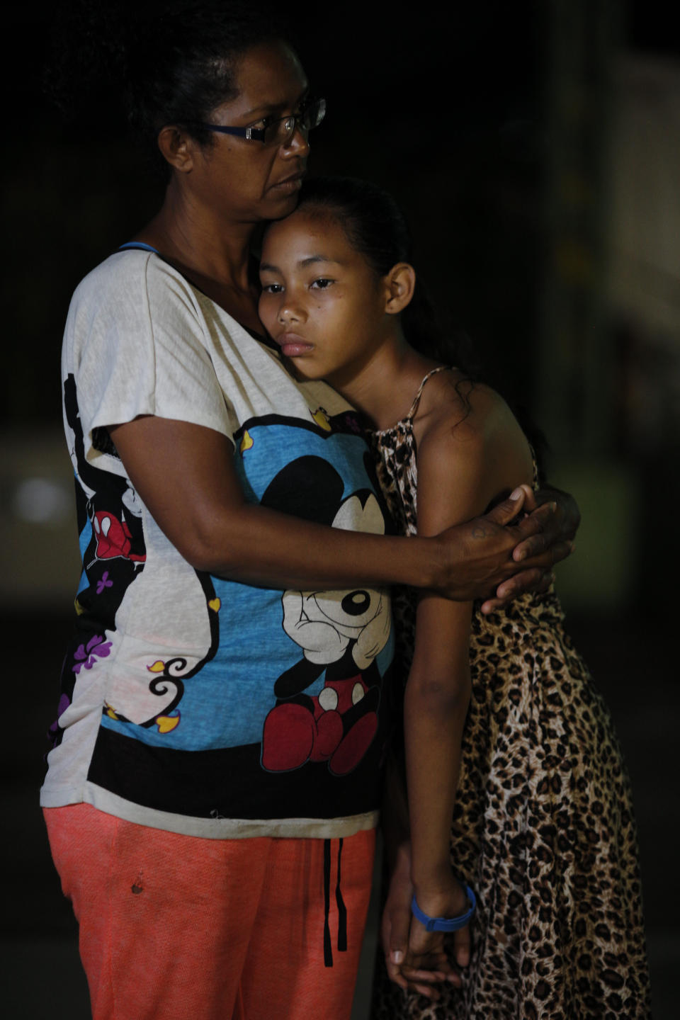 In this Sept. 4, 2018 photo, Venezuelan Sandra Cadiz and her 10-year-old daughter Angelis embrace after spending the night outside a Biomax gas station in a remote stretch of farmland known only as "Kilometer 17" in Santander state, Colombia, on their journey to Peru. A doctor had recently told Cadiz that her daughter was malnourished. The skinny 10-year-old was at least 10 pounds underweight and only eating twice a day. (AP Photo/Ariana Cubillos)