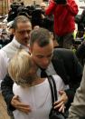 Olympic and Paralympic track star Oscar Pistorius (R) is hugged by a supporter as he arrives ahead of his trial for the murder of his girlfriend Reeva Steenkamp at the North Gauteng High Court in Pretoria, April 14, 2014. Pistorius is on trial for murdering Steenkamp at his suburban Pretoria home on Valentine's Day last year. He says he mistook her for an intruder. REUTERS/Siphiwe Sibeko (SOUTH AFRICA - Tags: SPORT ATHLETICS)