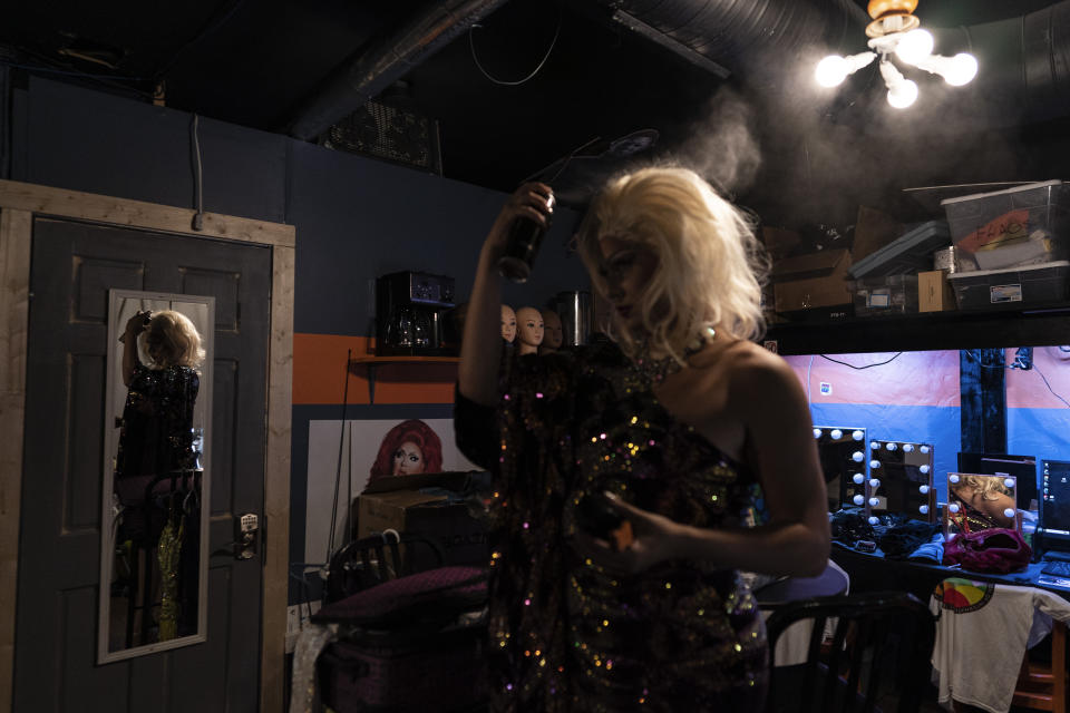 Drag queen Harpy Daniels, aka Joshua Kelley, applies hairspray before leaving the dressing area to perform at the Rainbow Special Interest Group of NAFSA: Association of International Educators reception at Pitchers and a League of Her Own bar in Washington, Wednesday, May 31, 2023. (AP Photo/Carolyn Kaster)