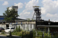 Cars sit outside the closed Wujek coal mine in Katowice, Poland, Saturday, July 4, 2020. The coronavirus has ripped through Poland's coal mines, where men descend deep underground in tightly packed elevators and work shoulder-to-shoulder. The virus hot spots, centered in the southern Silesia region, have paralyzed an already-troubled industry, forcing many to stay home from work and triggering a three-week closure of many state-run mines. (AP Photo/Czarek Sokolowski)