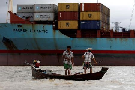 FILE PHOTO: Two fishermen stand on a boat in front of Myanmar industrial port terminal at the banks of the Hlaing river in Yangon, June 9, 2016. REUTERS/Soe Zeya Tun/File Photo