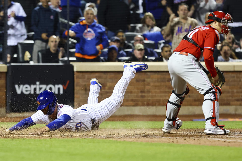 New York Mets designated hitter Pete Alonso, left, slides into home on an RBI-single by Dominic Smith as Philadelphia Phillies catcher J.T. Realmuto, right, looks on during the fifth inning of a baseball game, Sunday, May 1, 2022, in New York. (AP Photo/Jessie Alcheh)