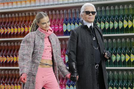 German designer Karl Lagerfeld (R) and model Cara Delevingne appear at the end of his Fall/Winter 2014-2015 women's ready-to-wear collection show for French fashion house Chanel at the Grand Palais transformed into a "Chanel Shopping Center" during Paris Fashion Week March 4, 2014. REUTERS/Stephane Mahe