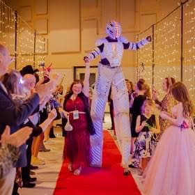 An honored guest walks the red carpet with a dancing “robot” performer. Image courtesy of Stacy McCormick.