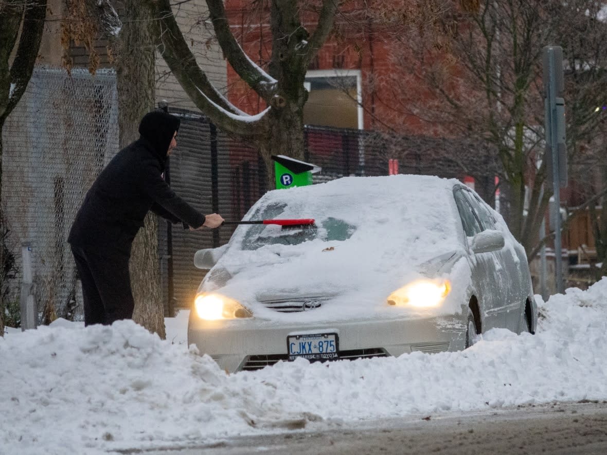 A person scrapes their car of snow and ice following a December storm in Ottawa. Environment Canada has issued winter storm warnings across the region, with heavy snow expected to begin falling Sunday evening. (Francis Ferland/CBC - image credit)