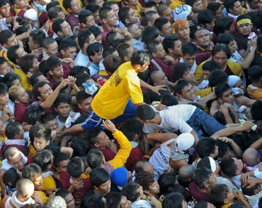 A Philippine Catholic pilgrim walks among a sea of devotees as he tries to reach for the statue of the Black Nazarene, a life-size icon of Jesus Christ carrying a cross during the annual religious procession in Manila on January 9, 2012. The "Black Nazarene" march is one of the most spectacular of many religious festivals that feature throughout the year, and police estimated between two and three million people turned up on Monday to be part of the crowd. AFP PHOTO/TED ALJIBE