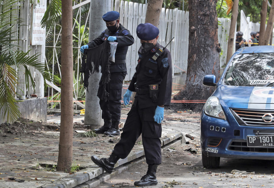 A member of the police bomb squad, left, holds a piece of clothes found at the site of Sunday's suicide bomb attack at the Sacred Heart of Jesus Cathedral in Makassar, South Sulawesi, Indonesia, Monday, March 29, 2021. Two attackers believed to be members of a militant network that pledged allegiance to the Islamic State group blew themselves up outside the packed Roman Catholic cathedral during a Palm Sunday Mass on Indonesia's Sulawesi island, wounding a number of people, police said. (AP Photo/Yusuf Wahil)