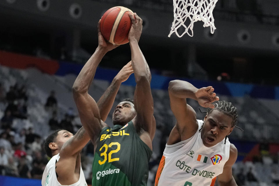 Brazil guard Georginho de Paula (32) drives against Ivory Coast guards Assemian Moulare (0) and Maxence Dadiet (7) during the Basketball World Cup group G match between Brazil and the Ivory Coast at the Indonesia Arena stadium in Jakarta, Indonesia, Wednesday, Aug. 30, 2023. (AP Photo/Achmad Ibrahim)