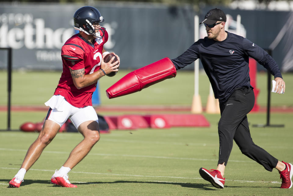 Houston Texans quarterback AJ McCarron (2) drops back to pass as he is chased by assistant quarterbacks coach T.J. Yates during an NFL training camp football practice Thursday, Aug. 20, 2020, in Houston. (Brett Coomer/Houston Chronicle via AP, Pool)