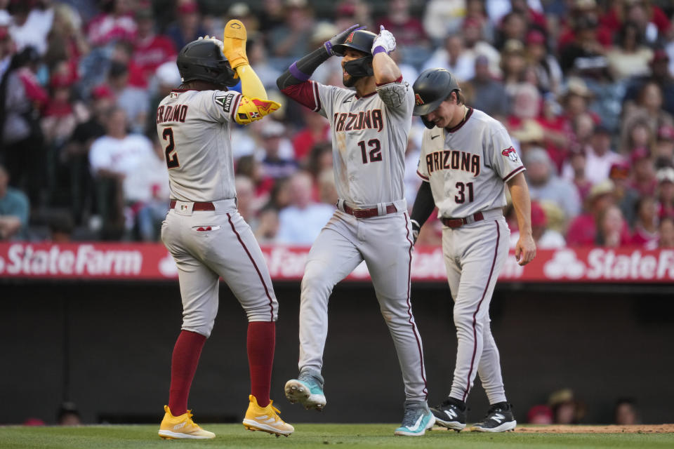 Arizona Diamondbacks designated hitter Lourdes Gurriel Jr. (12) celebrates with Geraldo Perdomo (2) and and Jake McCarthy (31) after hitting a grand slam during the second inning of a baseball game against the Los Angeles Angels in Anaheim, Calif., Friday, June 30, 2023. Ketel Marte also scored. (AP Photo/Ashley Landis)