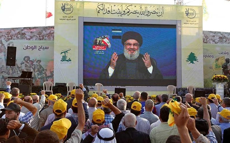 Hizbollah's Sayyed Hassan Nasrallah gestures as he addresses his supporters via a screen during a rally marking the anniversary of the defeat of militants near the Lebanese-Syrian border, in al-Ain village,  - Reuters