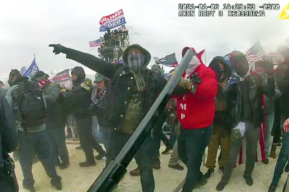 This image from police body-worn camera video, contained and annotated in the Justice Department's government's sentencing memorandum, supporting the sentencing of Brian Mock, shows Mock at the U.S. Capitol on Jan. 6, 2021, in Washington. Mock, the owner of a landscaping company and a former debt collector, was arrested for helping other rioters remove police barricades and committing four separate assaults against police officers who were attempting to block the rioters’ progression. (Department of Justice via AP)