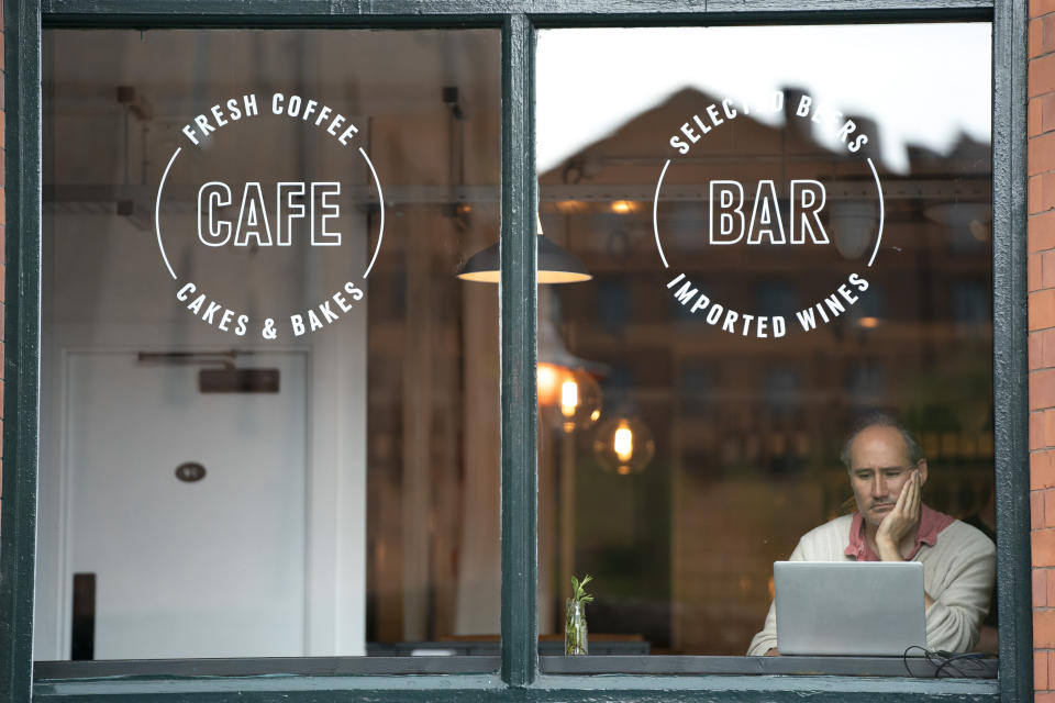 A man sits at his laptop in a cafe, as pubs, cafes and restaurants in England reopen indoors under the latest easing of the coronavirus lockdown, in Manchester, England, Monday, May 17, 2021. Pubs and restaurants across much of the U.K. are opening for indoor service for the first time since early January even as the prime minister urged people to be cautious amid the spread of a more contagious COVID-19 variant. (AP Photo Jon Super)