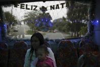 A mother with her daughter travel inside an urban bus decorated with Christmas motives while the bus driver Edilson (not pictured), 45, also known as "Fumassa", drives it in Santo Andre, outskirts of Sao Paulo December 10, 2013. Fumassa dresses as Santa Claus every year while driving his bus. Picture taken December 10. REUTERS/Nacho Doce (BRAZIL - Tags: SOCIETY TRANSPORT)