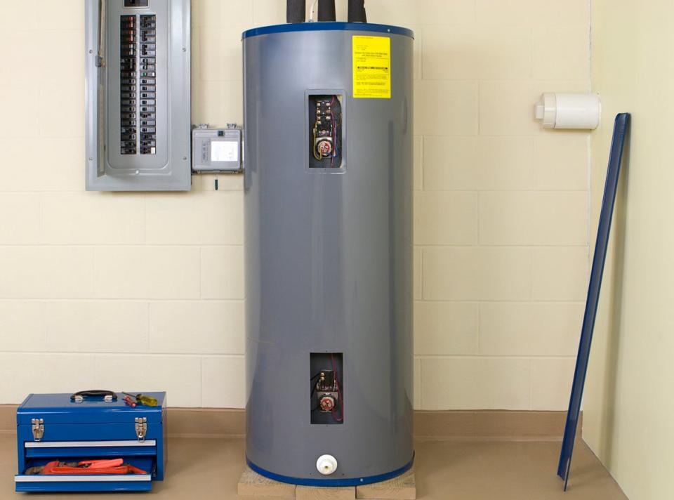 Residential water heater in white room with blue toolbox. 