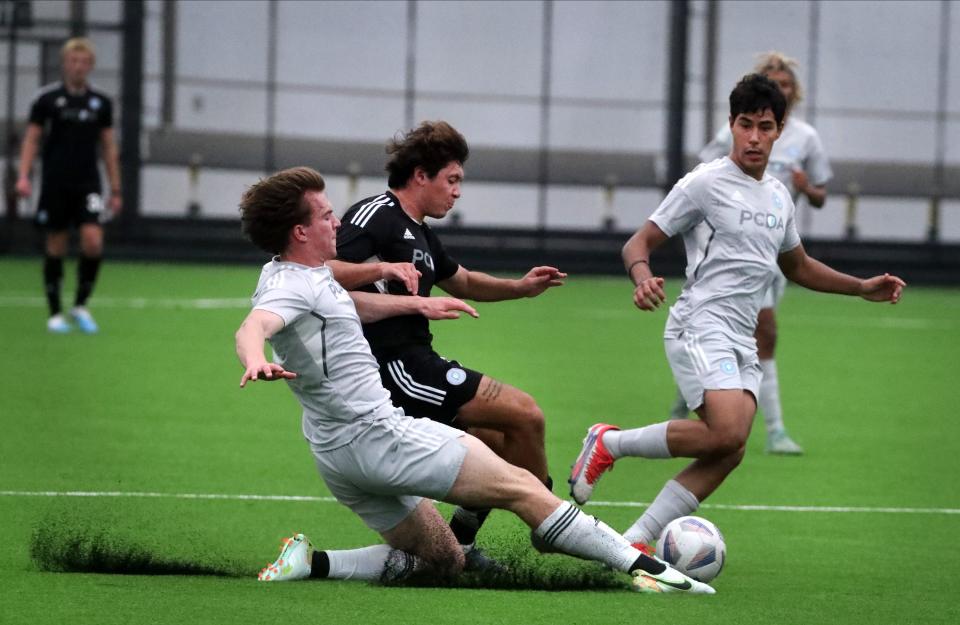 Members of the Pre-College Development Academy Sam Kaeding from Minnesota left and John Arguello from Colorado, center, both fight for the ball as Denilson Meza of Tennessee looks on as they practice in the new Siegel Park Indoor Soccer Park facility after a ribbon-cutting ceremony for the new building on Friday, March 24, 2023.