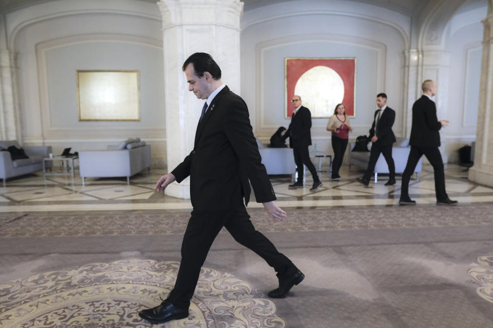 Caretaker prime minister of Romania, Ludovic Orban leaves after a press conference in Bucharest, Romania, Friday, March 13, 2020 after it was confirmed that a senator who attended several meetings in the building tested positive for the infection. The caretaker prime minister of Romania, Ludovic Orban, said in a press conference at the parliament, the government, including all ministers, as well as the leadership of the ruling National Liberal Party and all its senators, are going into quarantine after one of the governing party's senators, who took part in high-level meetings, who confirmed to be infected with the coronavirus. (AP Photo/George Calin)