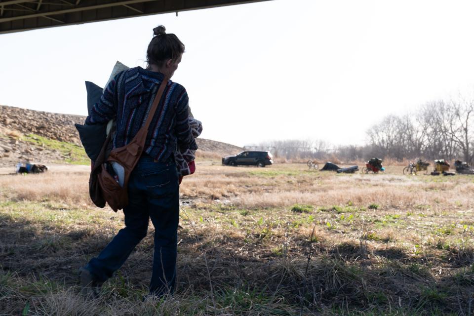 Kassie Blount carries away some of her possessions east of the N. Kansas Avenue Bridge on Tuesday morning after being removed from her camp by the Kansas River. The city of Topeka began enforcement of code violations regarding camping and fires within 500 feet of trails that include the Kansas River levee trail.