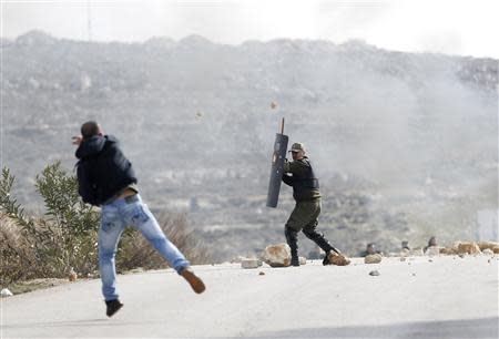 A demonstrator throws a stone at a member of the Palestinian security forces outside the Jalazoun refugee camp near the West Bank city of Ramallah January 12, 2014. REUTERS/Mohamad Torokman