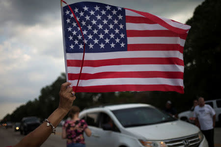 A woman waves the U.S. flag as samaritans offer water and food to residents who returned to their homes flooded by Tropical Storm Harvey in Houston, Texas, U.S. September 4, 2017. REUTERS/Adrees Latif