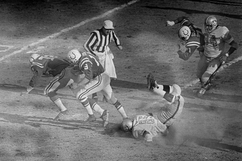 FILE - Baltimore Colts quarterback Johnny Unitas follows the blocking of Bob Vogel (72) as he runs for a first down to the Oakland Raiders 10-yard line during the first quarter of the AFC NFL football championship game at Memorial Stadium in Baltimore, Jan. 3, 1971. At right foreground, Raiders defender Carleton Oats slides head first on the ground. For the first time in 53 years, Baltimore is hosting the AFC championship game, bringing a different kind of spotlight to Charm City this weekend. (AP Photo/File)