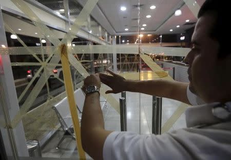 An employee of a car rental company tapes up a glass door as he prepares for Hurricane Patricia in Puerto Vallarta, Mexico October 22, 2015. REUTERS/Henry Romero