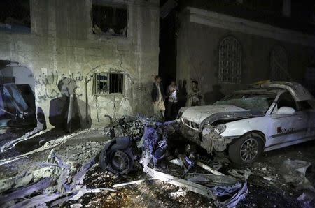 People stand next to wreckage at the site of a car bomb attack in Yemen's capital Sanaa June 29, 2015. REUTERS/Khaled Abdullah