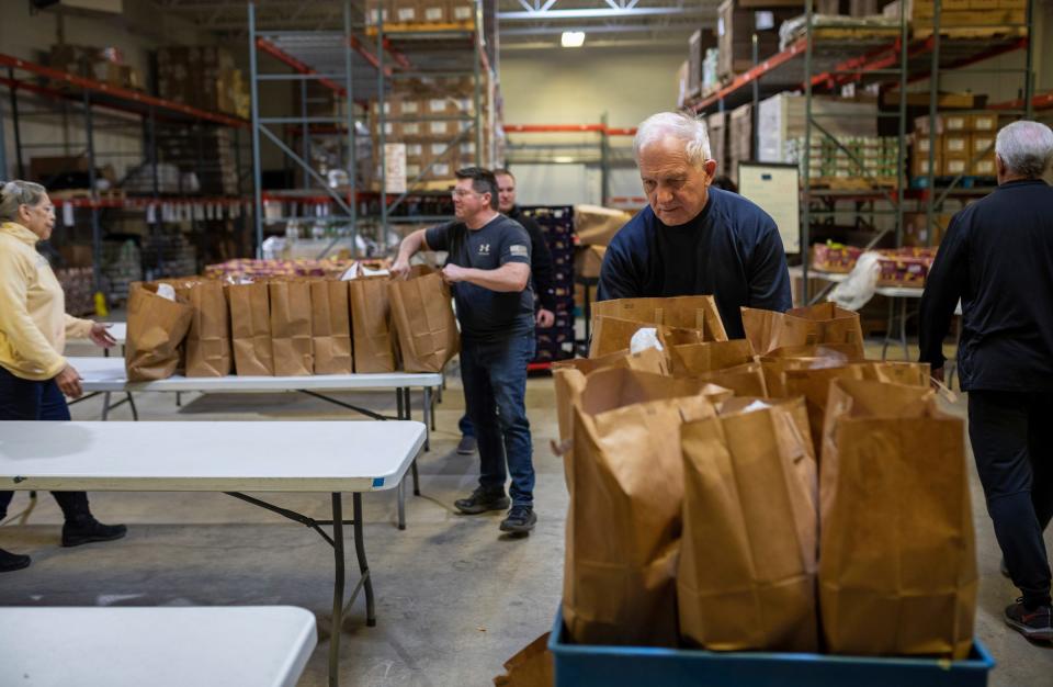 Vince Carter, a longtime volunteer, pushes a cart of bags filled with produce inside an emergency food warehouse run by Lighthouse, a nonprofit in Pontiac, on Wednesday, Jan. 24, 2024.