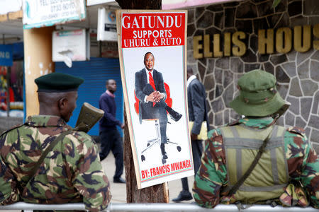 Policemen stand near a poster depicting Kenya's President Uhuru Kenyatta in Nairobi, Kenya November 20, 2017. REUTERS/Baz Ratner