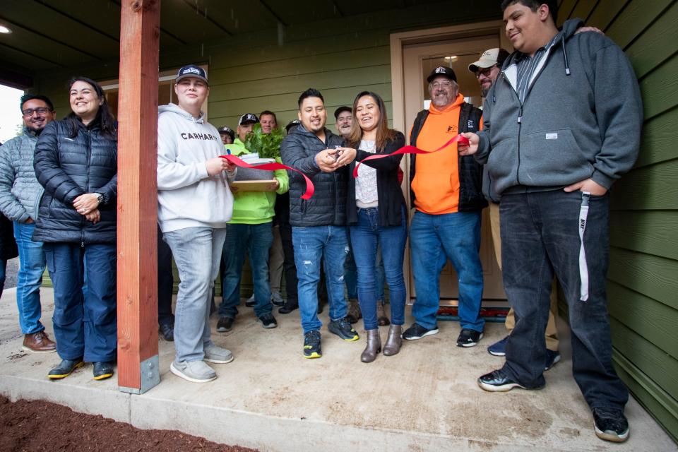 Heron Maya Ruiz, center left, and Margarita Vasquez Cruz cut a ribbon to celebrate their new home built by students in Eugene School District 4J’s Future Build career technical education program.