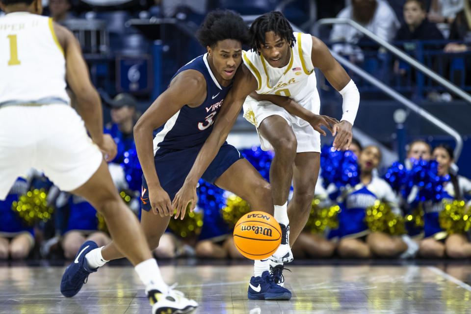 Virginia's Leon Bond III (35) and Notre Dame's Carey Booth (0) fight for a loose ball during the first half of an NCAA college basketball game on Saturday, Dec. 30, 2023, in South Bend, Ind. (AP Photo/Michael Caterina)