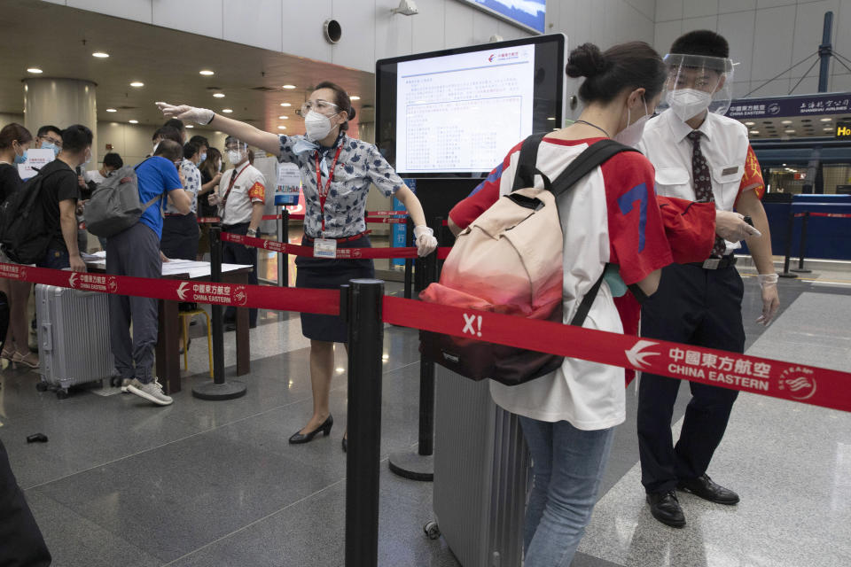 Empleados de aerolíneas redirigen a una viajera el miércoles 17 de junio de 2020 en un punto de control de pasajeros llegados de zonas de alto riesgo, para que presenten los resultados de sus pruebas de COVID-19 antes de abordar su vuelo desde el Aeropuerto Beijing Capital, en Beijing. (AP Foto/Ng Han Guan)