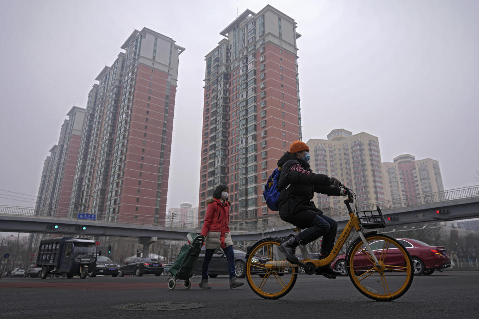 People wearing face masks to help protect from the coronavirus cross an intersection in Fengtai District in Beijing, Monday, Jan. 24, 2022. Chinese authorities have lifted a monthlong lockdown of Xi'an and its 13 million residents as infections subside ahead of the Winter Olympics. Meanwhile, the 2 million residents of one Beijing district are being tested following a series of cases in the capital. (AP Photo/Andy Wong)