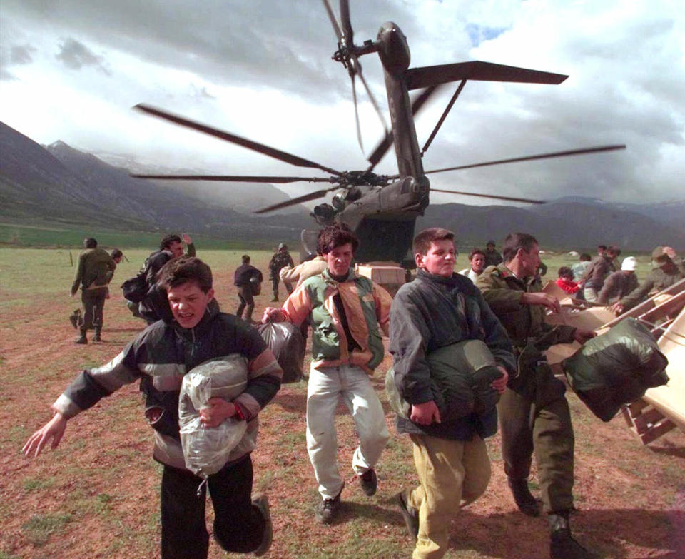 FILE - Albanians and ethnic Albanian refugees run from a U.S. Navy helicopter after taking humanitarian aid, during a what amounted to a frenzy, near the town of Kukes, Albania, on April 13, 1999. People mobbed the U.S. helicopters causing pandemonium on the tiny airstrip near the Kosovo-Albania border. Former award-winning Associated Press photographer John Gaps III, who documented everything from war zones to the NCAA College World Series during his career, was found dead at his home Monday, Oct. 17, 2022, in Des Moines, Iowa, his family confirmed Tuesday. He was 63.(AP Photo/John Gaps III)