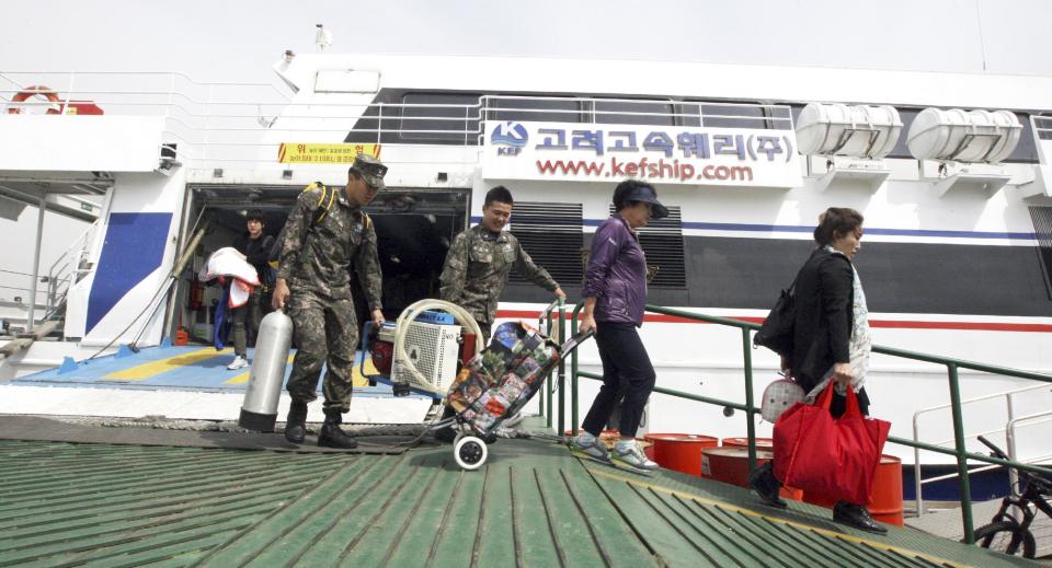 Local residents and marines exit a ship which was scheduled to leave for Yeonpyeong island, after its trip was canceled at Incheon port in Incheon, west of Seoul, South Korea, Monday, March 31, 2014. South Korea on Monday returned fire into North Korean waters after shells from a North Korean live-fire drill fell south of the rivals' disputed western sea boundary, a South Korean military official said. Residents on the front-line South Korean island said they were evacuated to shelters during the exchange. (AP Photo/Bae Sang-hee, Yonhap) KOREA OUT