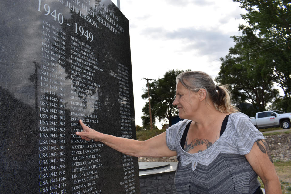 Dana Amon finds the name of her stepfather who fought in World War II on a monument at Veterans Memorial Park, Aug. 25, 2021, in Watford City, N.D. Amon, who grew up in a double-wide trailer on a farm on the edge of the county seat, Watford City, remembers riding her horse across fields now dotted with tracts of modest housing lit up at night by the flares from nearby oil wells. “Our little town just blew up at the seams,” she said. (AP Photo/Matthew Brown)