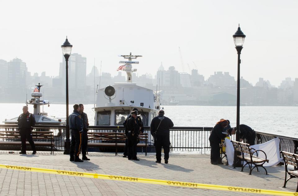 Police investigate the scene after divers found the bodies of two people, right, in the Hudson River near Sinatra Park, Sunday, April 13, 2014 in Hoboken, N.J. Police have not identified the victims. (AP Photo/Joe Epstein)