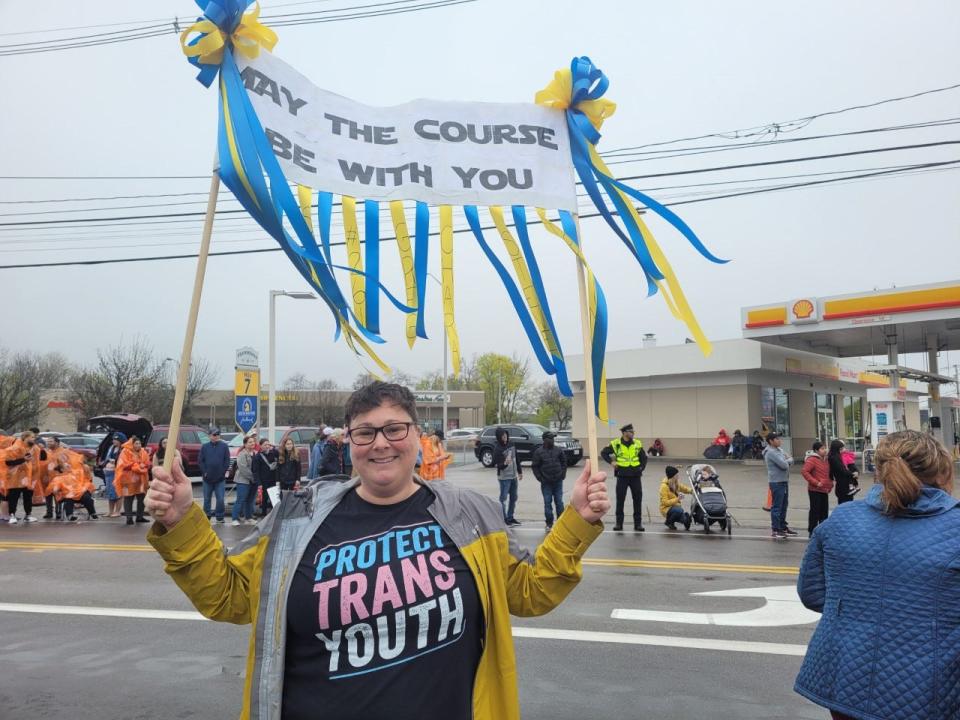 Stacey Lee, of Framingham, holds up a homemade sign while watching the Boston Marathon in Framingham, April 17, 2023. Lee's sign contains names written on the ribbons for different runners. She has been watching the Marathon for 15 years.