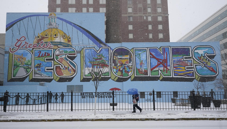 A pedestrian walks down a snow covered sidewalk, Monday, Jan. 25, 2021, in downtown Des Moines, Iowa. A major winter storm is expected to blanket a large swath of the middle of the country with snow Monday and disrupt travel as more than a foot of snow falls in some areas. (AP Photo/Charlie Neibergall)