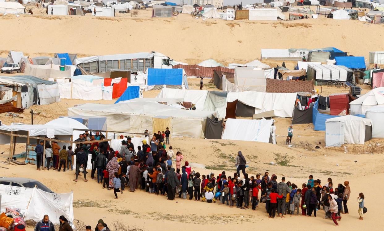 <span>Displaced Palestinians wait to receive food at a tent camp in Rafah.</span><span>Photograph: Ibraheem Abu Mustafa/Reuters</span>