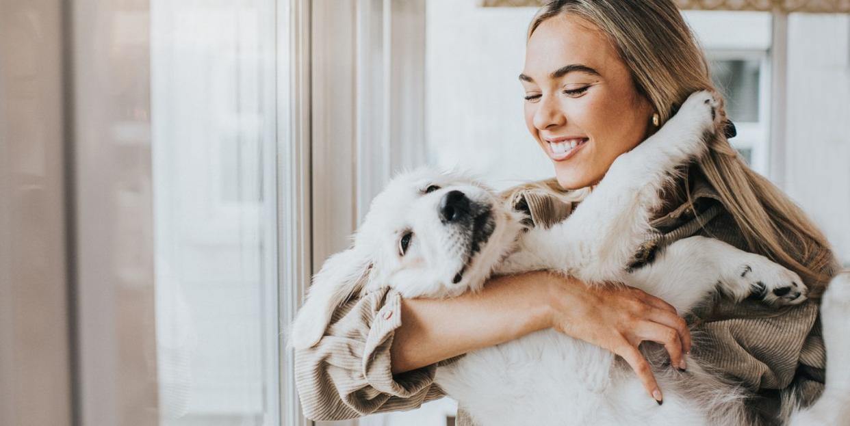 young woman cuddles her 12 week old golden retriever puppy