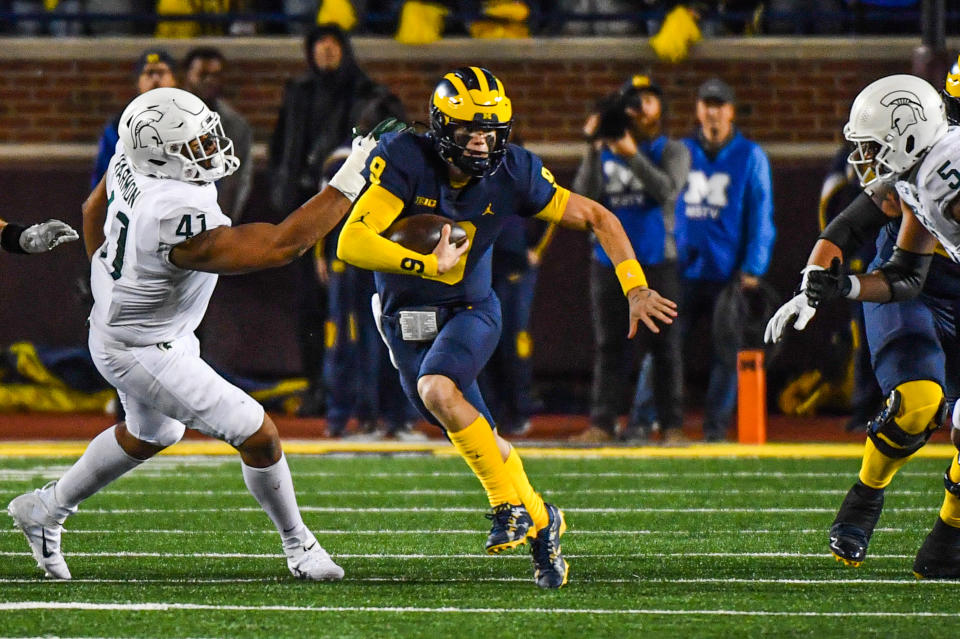 ANN ARBOR, MICHIGAN - OCTOBER 29: J.J. McCarthy #9 of the Michigan Wolverines runs with the ball and avoids a tackle by Derrick Harmon #41 of the Michigan State Spartans during the first half of a college football game at Michigan Stadium on October 29, 2022 in Ann Arbor, Michigan. (Photo by Aaron J. Thornton/Getty Images)