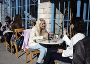 People sit on a coffee shop as cafes, restaurants and other eateries reopened in some provinces across the country, in Ankara, Turkey, Wednesday, March 3, 2021. The businesses are allowed to operate at half-capacity between the hours of 7:00 a.m. and 07:00 p.m. as coronavirus restrictions are eased. (AP Photo/Burhan Ozbilici)