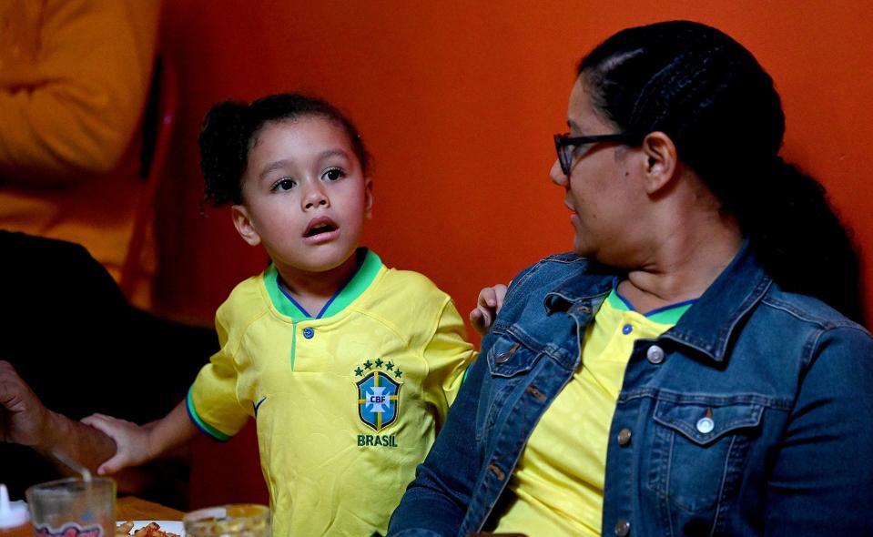 Giulia Valle, 3, of Framingham, watches the World Cup soccer match between Brazil and Cameroon with her mother, Juliane Valle, at the Tropical Cafe in downtown Framingham, Dec. 2, 2022.
