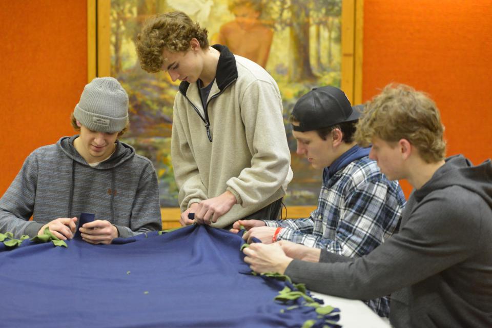 Chase Semprini, Doug Carr, Conor Cattabriga and Coley Buckler, left to right, work together Tuesday to assemble blankets for the homeless at the First Baptist Church of Hyannis. The students are members of the Barnstable High School hockey team.